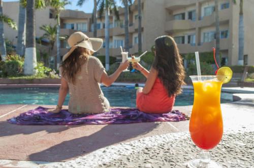 圣卡洛斯特塔卡维庄园酒店的两个女孩坐在游泳池旁边,喝着饮料