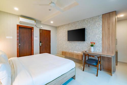 海得拉巴Harvey's Hotels (Gachibowli)的一间卧室配有一张床、一张书桌和一台电视。