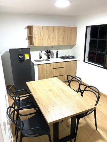 麦德林Villa Estadio的厨房配有木桌、椅子和冰箱。