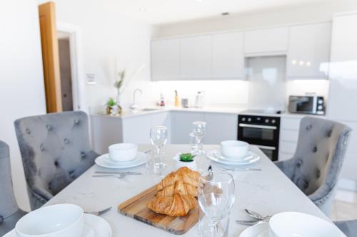 卡迪夫Luxury Cardiff City Centre Apartments的白色的厨房,配有一张桌子和一盘食物