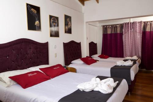库斯科Hotel Feimar的一间设有三张床的房间,上面有红色和白色的毛巾