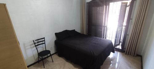 圣玛丽亚Quarto em casa a 1.4km da UFSM的卧室配有床、椅子和窗户。