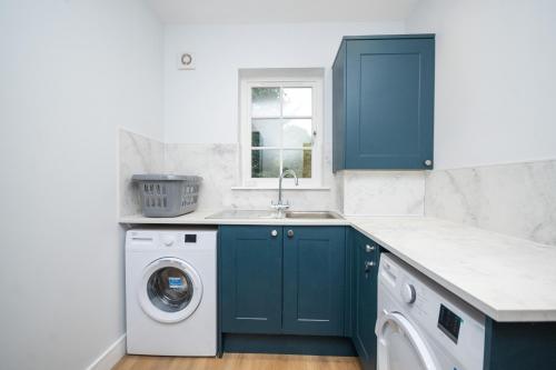 邓布兰Historical Holmehill Lodge的厨房配有蓝色橱柜和洗衣机。