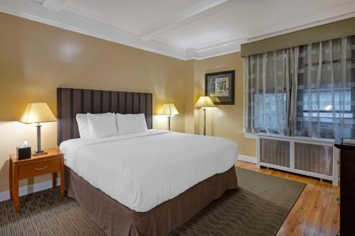 纽约贝斯特韦斯特款待套房酒店的一间卧室设有一张大床和一个窗户。