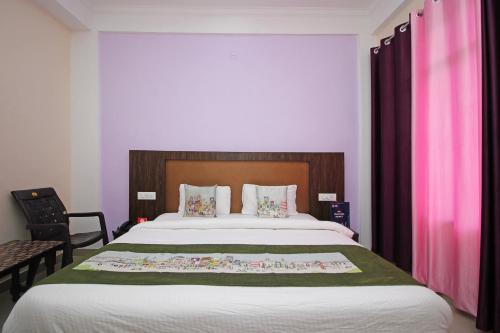 达兰萨拉OYO Hotel Chandni的一间卧室配有一张带粉红色窗帘的大床