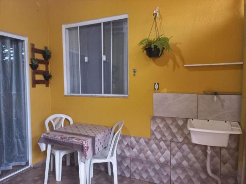 阿拉亚尔-杜卡布Kitnet Arraial do Cabo, Monte Alto.的黄色客房内的桌椅,设有水槽