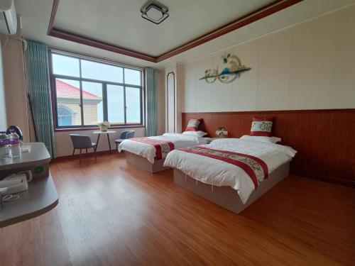 莆田湄洲岛云上居民宿 的一间卧室设有两张床、一张桌子和一个窗口