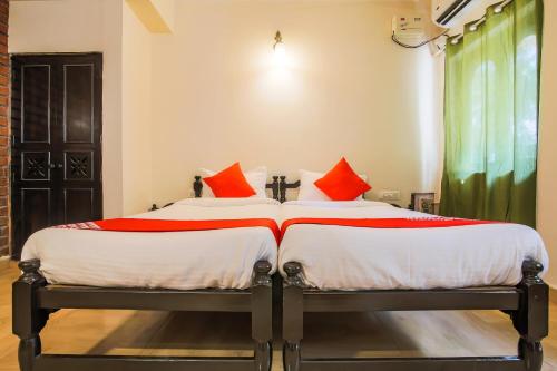 ChicolnaOYO La Petite Near Dabolim Airport的一间卧室配有两张带红色枕头的床