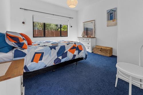 帕帕莫阿Poolside Serenity - Papamoa Beach Holiday Home的一间卧室配有一张床、一张桌子和一个窗户。