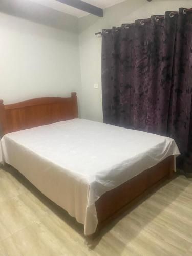 NausoriHasmat Road的一间卧室配有一张带白色床单和窗帘的床