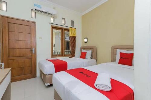 诗都阿佐OYO 91292 Pondok Inap Shofwa 1的一间卧室配有两张红色和白色床单