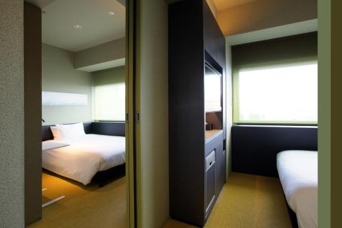 大阪remm Shin-Osaka的一间小卧室,配有两张床和镜子