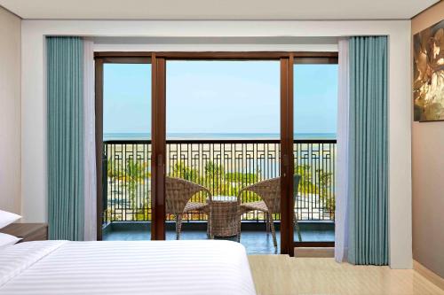 丹戎潘丹万豪贝利唐菲尔德酒店的一间卧室配有一张床,阳台配有桌子
