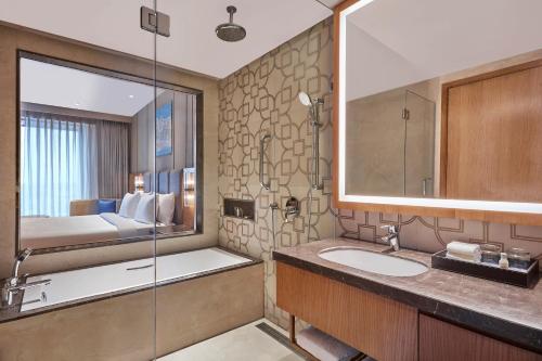 瓦拉纳西Doubletree By Hilton Varanasi的一间带水槽和淋浴的浴室以及一张床