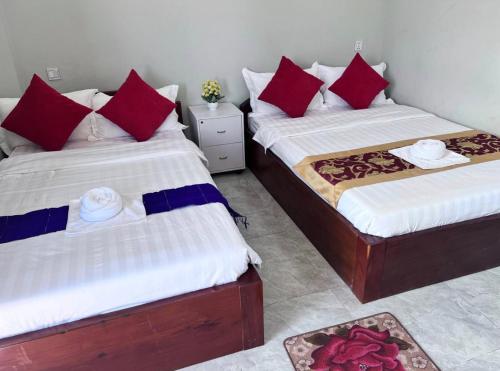 贡布Kro Nhep Guesthouse的两张床铺,房间配有红色和蓝色枕头