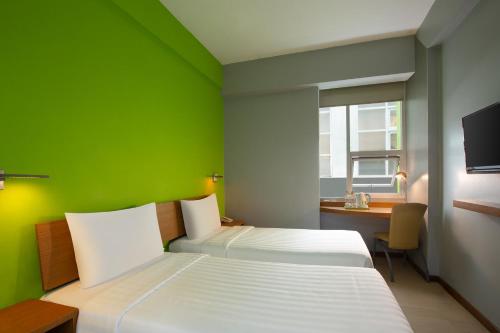 日惹日惹马里奥神童酒店的一间卧室设有两张床、一张桌子和一面绿色的墙壁
