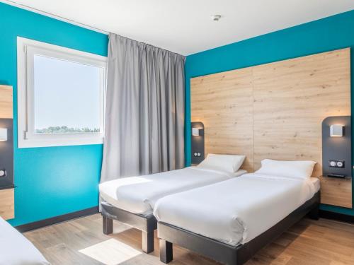 克罗的圣马丁B&B HOTEL Saint-Martin-de-Crau Alpilles Camargue的蓝色墙壁客房的两张床