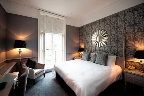 斯托克绿林SPA酒店的卧室配有一张白色大床和一把椅子