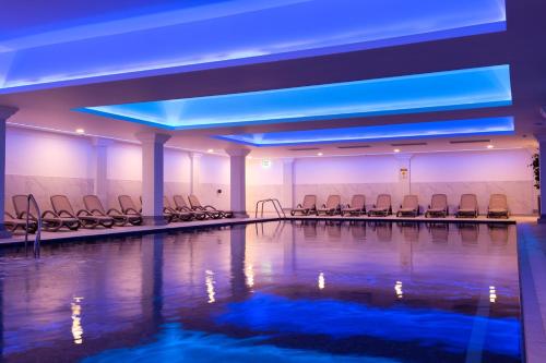 斯托克绿林SPA酒店的一个带椅子的游泳池,位于蓝色灯光的房间