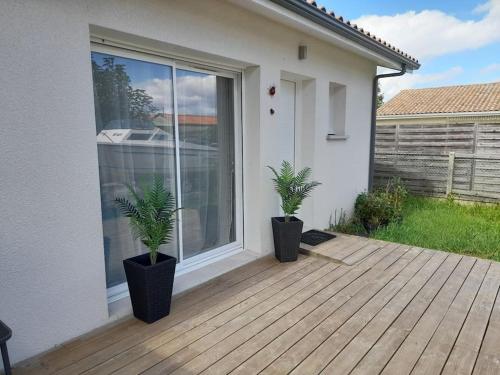 居让梅斯特拉Studio tout confort + terrasse的两株盆栽植物坐在房子前面的甲板上