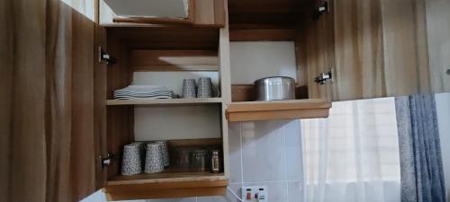 RuiruPremier Stays Ruiru的厨房配有带盘子和平底锅的木制橱柜