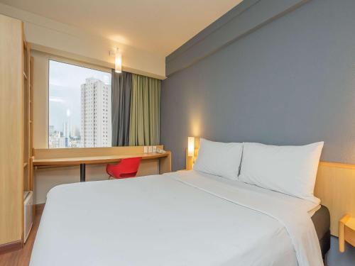 瓜鲁柳斯ibis Guarulhos Aeroporto的配有一张床、一张书桌和一扇窗户的酒店客房