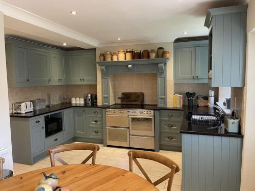 法纳姆Cottage 2, Northbrook Park, Farnham-up to 6 adults的厨房配有蓝色橱柜和木桌