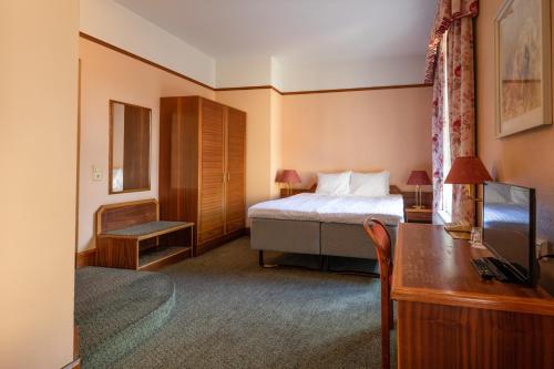 派尔努维多利亚酒店的酒店客房配有一张床、一张书桌和一台电视。