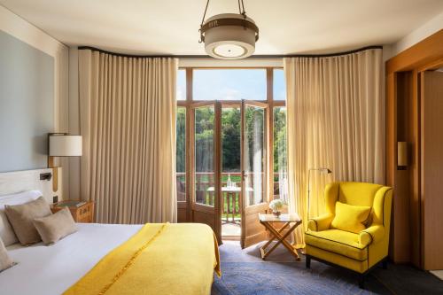 埃维昂莱班罗亚酒店的一间卧室配有床、黄椅和窗户