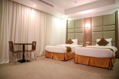 吉达Areen Hotel Al Basateen的酒店客房设有两张床和一张桌子。