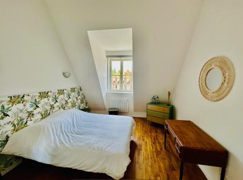 日安L'Herboriste - Appartements meublés的一间卧室配有一张床、镜子和一张桌子