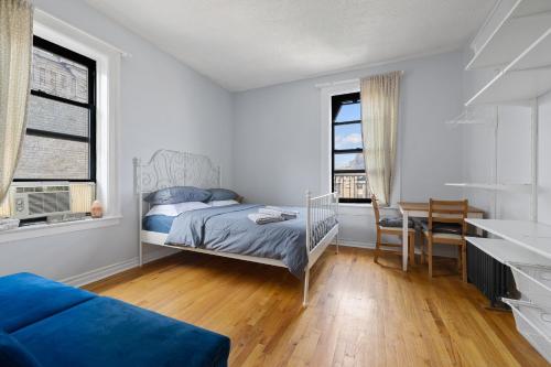 纽约Live Upper Manhattan on a Budget的一间卧室配有一张床、一张书桌和两个窗户。