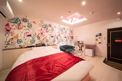 京都Hotel　このへんのアジア的一间设有红色床单和花卉壁纸的床的客房