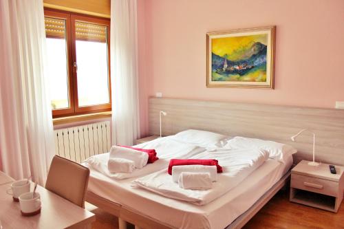 塔尔维西奥Adriatico Rooms的卧室配有白色的床和红色枕头