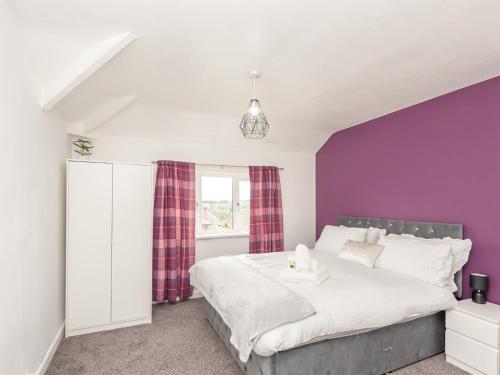 利兹Pass the Keys Large Family Getaway的一间卧室配有一张大床和紫色墙壁