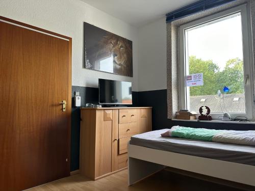 波鸿Modernes Apartment 5 , 6 und 7 in Bochum的一间卧室配有一张床、一台电视和一个窗口