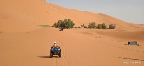 AdrouineMerzouga Chebbi camp的骑摩托车在沙漠中的人