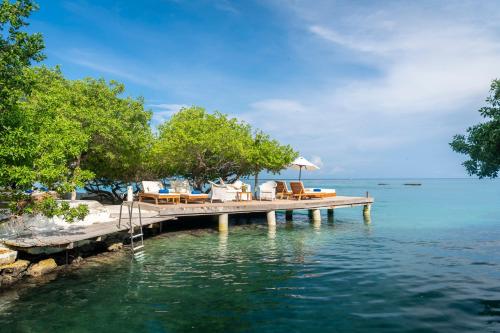 格兰德岛Hotel Coralina Island的水面上带椅子和遮阳伞的码头