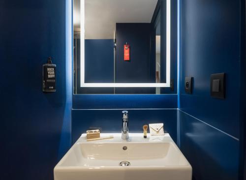 巴黎Ibis Paris Gare Montparnasse Catalogne的蓝色的浴室设有白色水槽和镜子