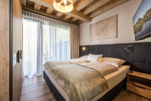 迈尔霍芬Natur Zeit - Alpine Garden Apartments的一间卧室设有一张大床和一个大窗户