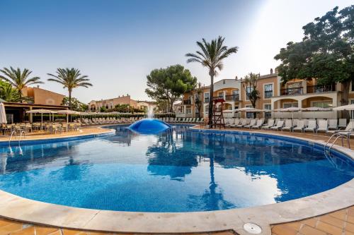 卡兰博希Zafiro Menorca的棕榈树和建筑度假村的游泳池