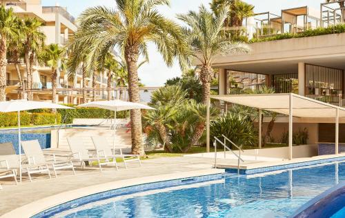 阿尔库迪亚港萨菲罗宫西拉斯酒店的一座带椅子和遮阳伞的游泳池位于一座建筑旁边