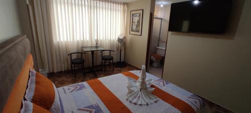 利马Aruba Suite Hotel的一间卧室配有一张带电视和桌子的床。