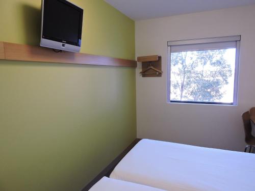 悉尼宜必思快捷酒店 - 悉尼奥林匹克公园的卧室配有一张床,墙上配有电视。