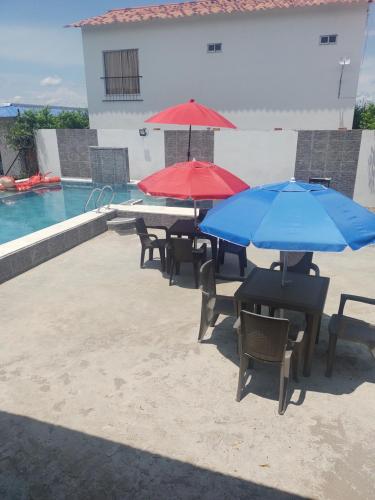 吉拉尔多特Casa Vacacional Quinta Sofia的一组桌子,在游泳池旁边配有遮阳伞