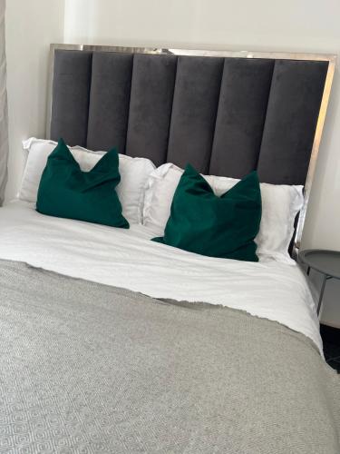 博勒姆伍德Borehamwood stay的一张大床,上面有两个绿色枕头