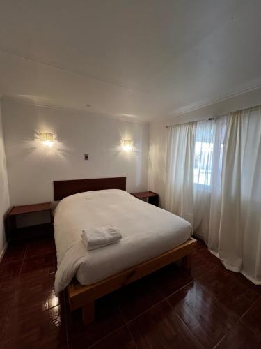 皮卡Hospedaje la Florentina的卧室配有一张带白色床单的大床和窗户。