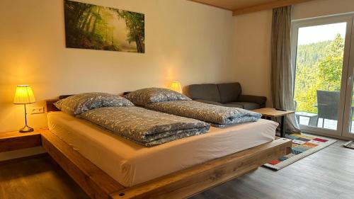 费尔德伯格Greenhaus的一间卧室配有一张床、一张沙发和一个窗口