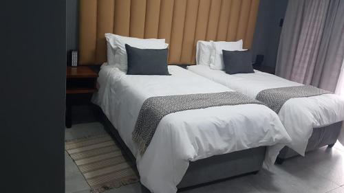 伯格斯堡Honolulu Lifestyle Guest Lodge的配有2张床铺的酒店客房,提供白色床单和枕头