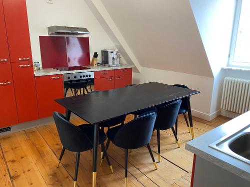 曼海姆Stadthaus Room 2 mit Hochbett for 3 Persons or Eltern mit 2 Kindern的红色橱柜厨房里的一张黑桌子和椅子